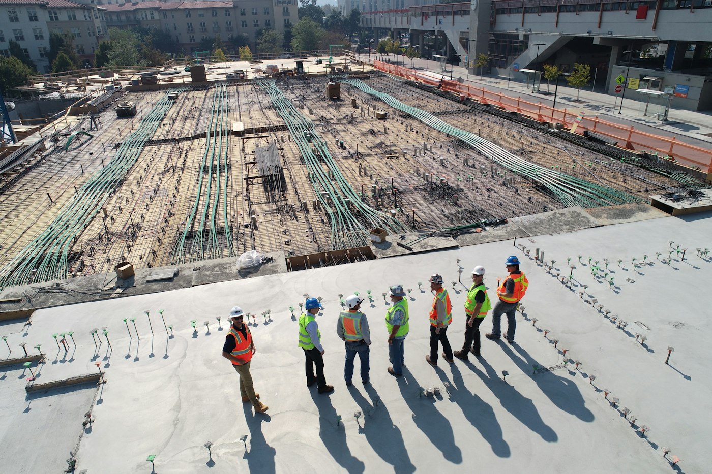 Cuadrilla en una losa de obra, de pie frente a una estructura a medio levantar.